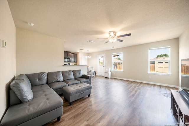 6516 Sabinal, San Antonio, TX 78252 - living area featuring a ceiling fan, dark wood finished floors, baseboards, a chandelier, and a textured ceiling