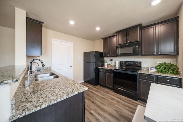 6516 Sabinal, San Antonio, TX 78252 - kitchen with black appliances, a sink, light wood-style floors, dark brown cabinetry, and light stone counters