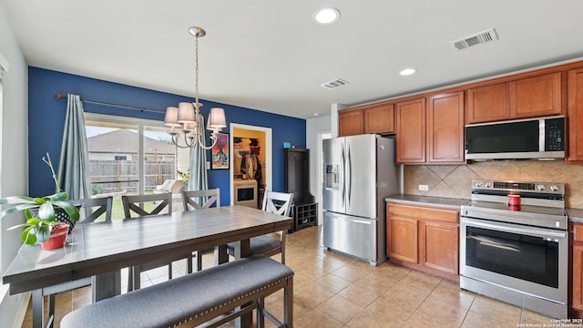 760 Guna, New Braunfels, TX 78130 - kitchen with appliances with stainless steel finishes, a chandelier, decorative backsplash, brown cabinets, and hanging light fixtures