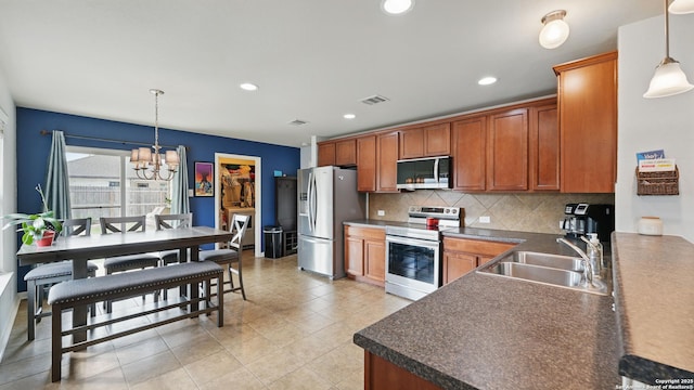 760 Guna, New Braunfels, TX 78130 - kitchen with stainless steel appliances, a sink, dark countertops, tasteful backsplash, and a chandelier