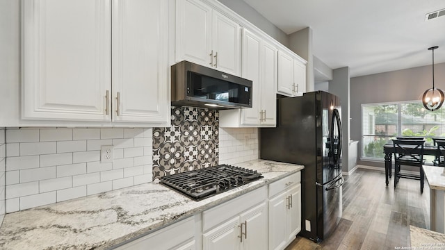 14534 Gunter Ave, San Antonio, TX 78254 - kitchen with stainless steel microwave, freestanding refrigerator, white cabinets, and wood finished floors