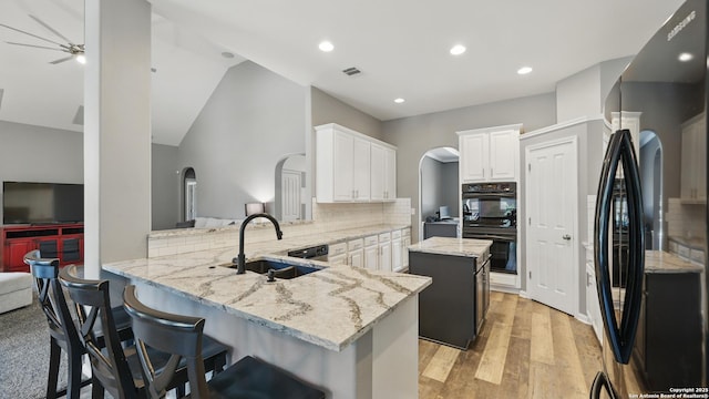 14534 Gunter Ave, San Antonio, TX 78254 - kitchen with black appliances, a sink, arched walkways, a peninsula, and a kitchen island