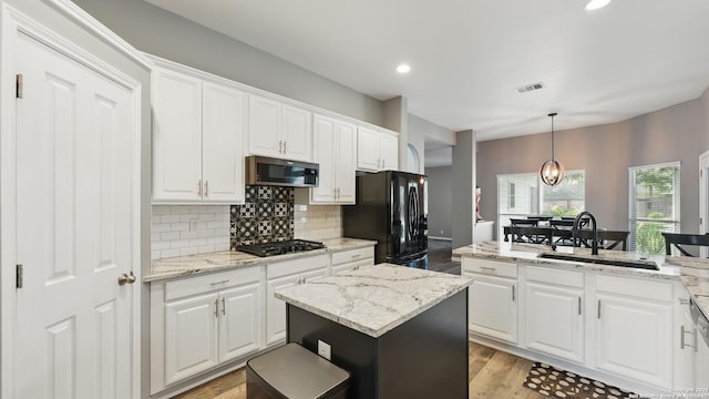 14534 Gunter Ave, San Antonio, TX 78254 - kitchen with black appliances, a sink, white cabinetry, light wood finished floors, and tasteful backsplash