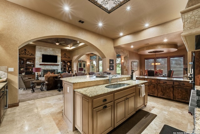 44 Oakland, Boerne, TX 78006 - kitchen with a sink, a large fireplace, a center island with sink, ceiling fan, and arched walkways