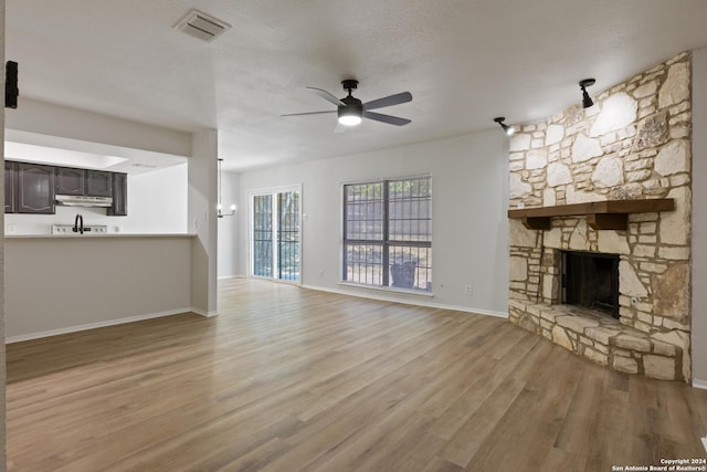 1102 Fillmore Dr, San Antonio, TX 78245 - unfurnished living room featuring wood finished floors, ceiling fan, a stone fireplace, and baseboards