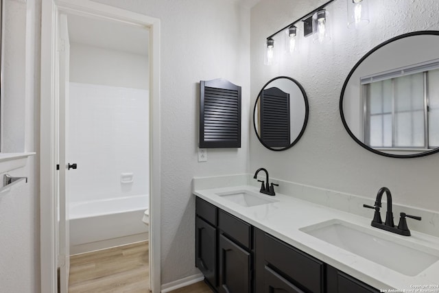 1102 Fillmore Dr, San Antonio, TX 78245 - bathroom featuring wood finished floors, double vanity, and a textured wall