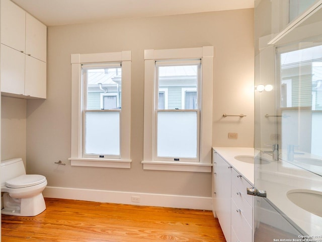 302 Cedar, San Antonio, TX 78210 - bathroom featuring wood finished floors, baseboards, double vanity, and toilet