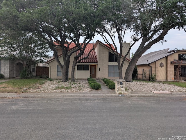 6410 Firestone, San Antonio, TX 78244 - view of front of property featuring fence, a tile roof, brick siding, and a chimney