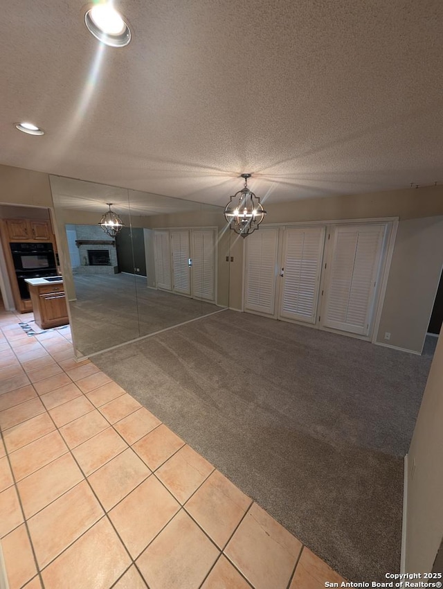 6410 Firestone, San Antonio, TX 78244 - unfurnished living room featuring a chandelier, light colored carpet, a fireplace, light tile patterned floors, and a textured ceiling