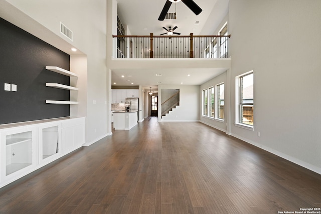 12414 Mineshaft, San Antonio, TX 78254 - unfurnished living room featuring a ceiling fan, a high ceiling, dark wood-type flooring, baseboards, and stairway