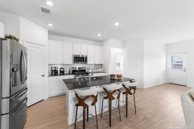 5903 Geronimo, Seguin, TX 78155 - kitchen with stainless steel appliances, a kitchen breakfast bar, a sink, light wood-style floors, and white cabinetry