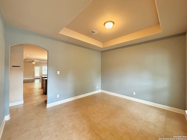 7622 Ruger Rnch, San Antonio, TX 78254 - spare room with arched walkways, a tray ceiling, a ceiling fan, and light tile patterned floors