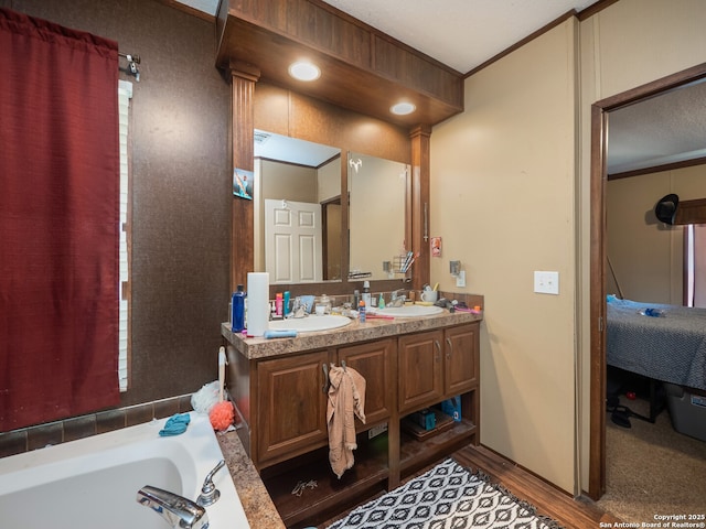 15411 Cranes Mill Rd, Canyon Lake, TX 78133 - bathroom featuring ornamental molding, wood finished floors, double vanity, and a bath