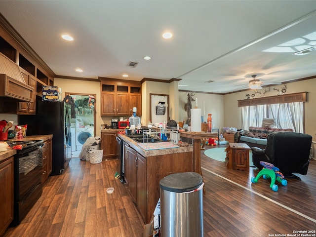 15411 Cranes Mill Rd, Canyon Lake, TX 78133 - kitchen featuring washing machine and dryer, black appliances, crown molding, open floor plan, and dark wood-style floors