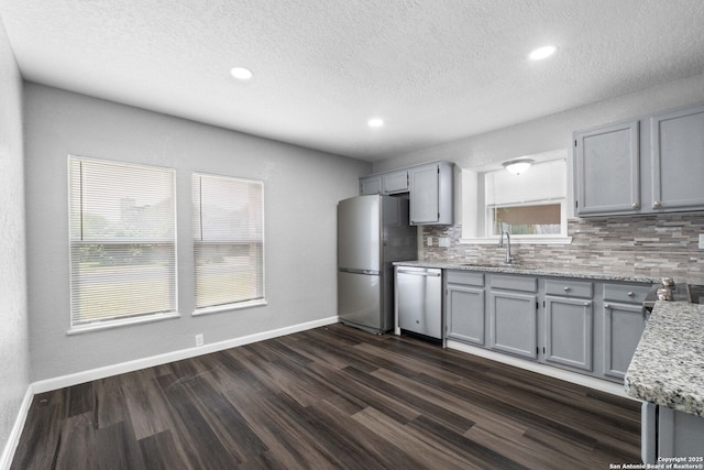 6909 Quail Lk, San Antonio, TX 78244 - kitchen featuring stainless steel appliances, a sink, gray cabinetry, backsplash, and a textured ceiling