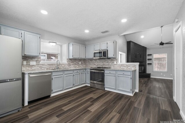 6909 Quail Lk, San Antonio, TX 78244 - kitchen featuring appliances with stainless steel finishes, a sink, decorative backsplash, dark wood-style floors, and a textured ceiling
