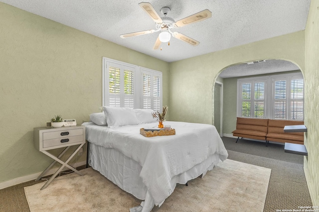 1605 W Winnipeg, San Antonio, TX 78225 - carpeted bedroom featuring arched walkways, a textured ceiling, a textured wall, ceiling fan, and baseboards