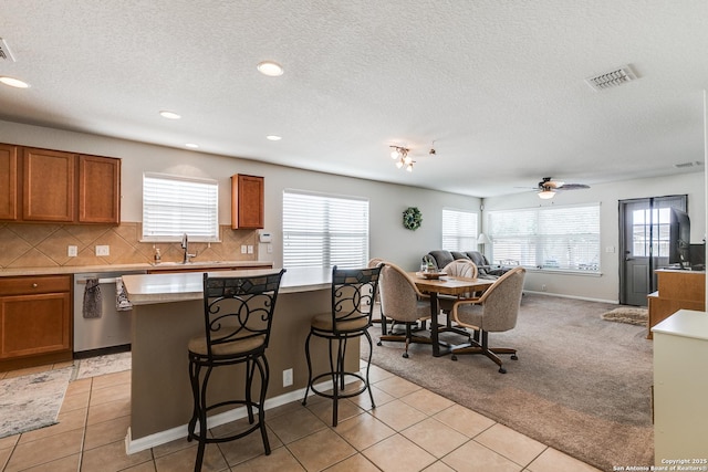 11014 Palomino, San Antonio, TX 78245 - kitchen with stainless steel dishwasher, plenty of natural light, open floor plan, brown cabinetry, and recessed lighting
