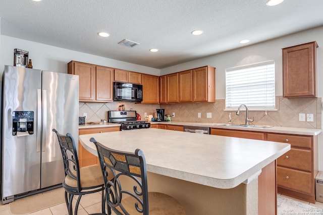 11014 Palomino, San Antonio, TX 78245 - kitchen with appliances with stainless steel finishes, a sink, a breakfast bar, light countertops, and a center island