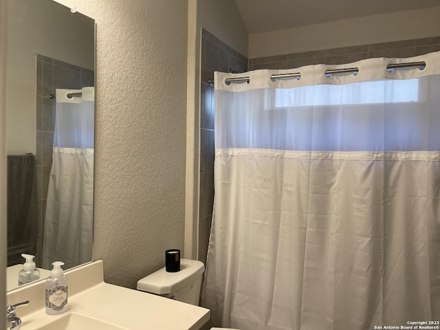 full bath featuring a textured wall, vanity, curtained shower, and toilet