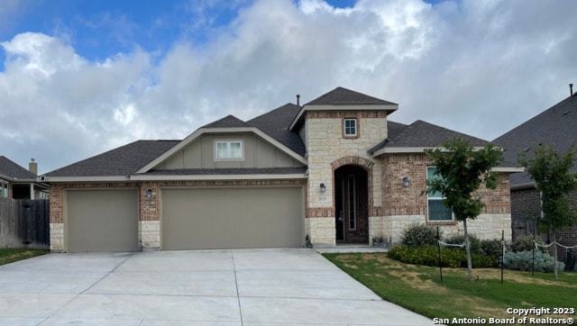 french country inspired facade featuring an attached garage, brick siding, and stone siding