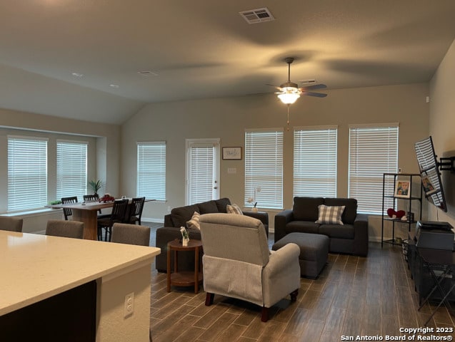 living room featuring dark wood finished floors, lofted ceiling, a ceiling fan, and baseboards