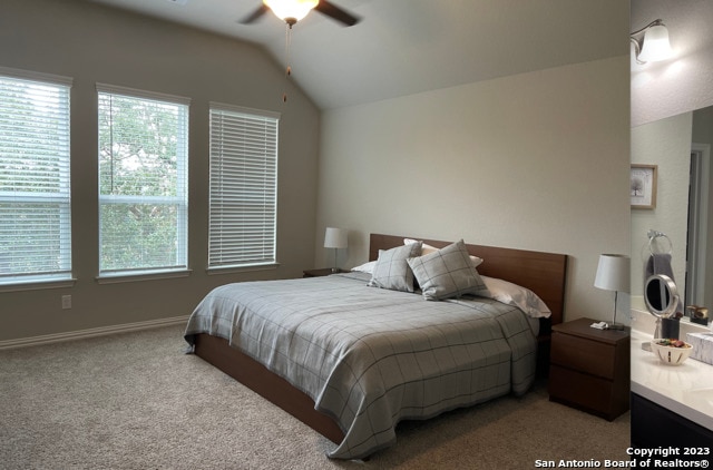 carpeted bedroom with lofted ceiling, a ceiling fan, and baseboards