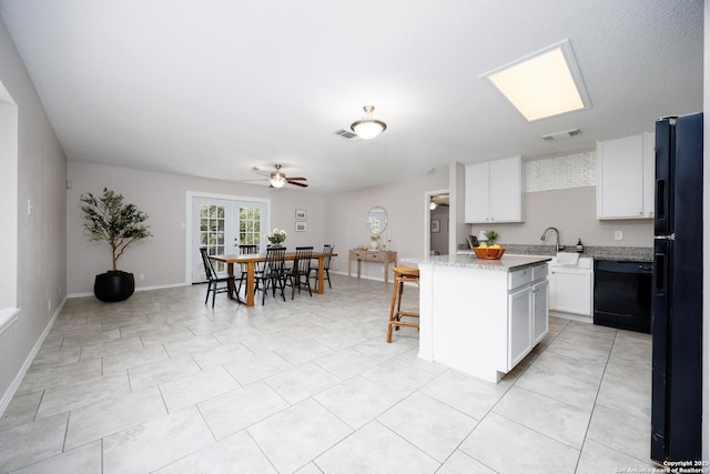 10511 Stone Crk, San Antonio, TX 78254 - kitchen featuring black appliances, ceiling fan, a center island, white cabinetry, and light stone countertops