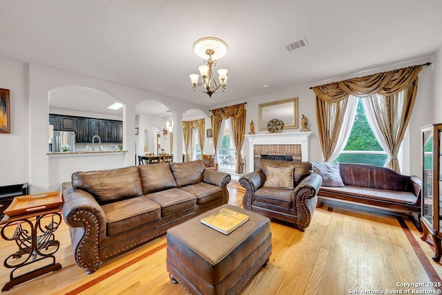 13619 Mesa Pt, San Antonio, TX 78232 - living area featuring arched walkways, a chandelier, light wood-type flooring, and a fireplace