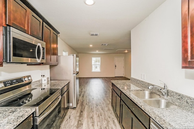 527 Elley, Seguin, TX 78155 - kitchen with appliances with stainless steel finishes, a sink, light wood-style floors, open floor plan, and light stone counters