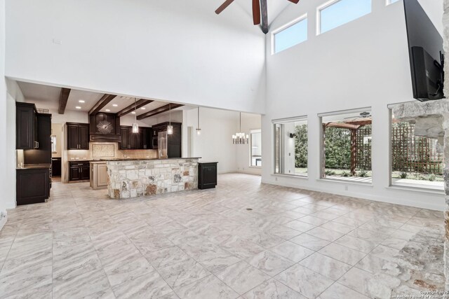 6327 Almeria Cir, San Antonio, TX 78257 - unfurnished living room with beam ceiling, ceiling fan, a high ceiling, a chandelier, and light marble finish floors