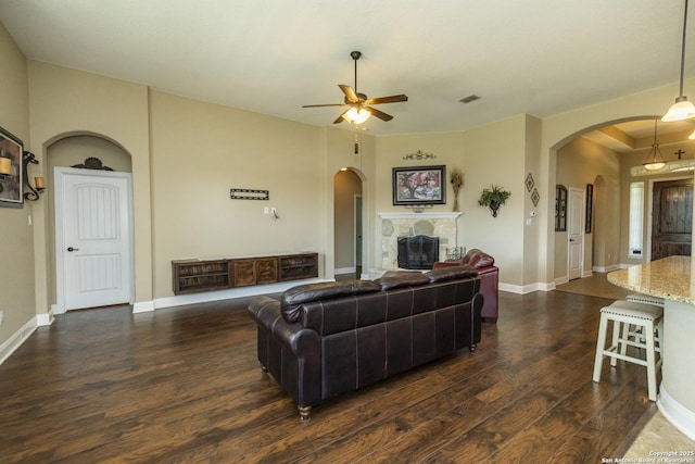 3308 Ashleys, Marion, TX 78124 - living area with arched walkways, dark wood-style floors, a ceiling fan, a glass covered fireplace, and baseboards