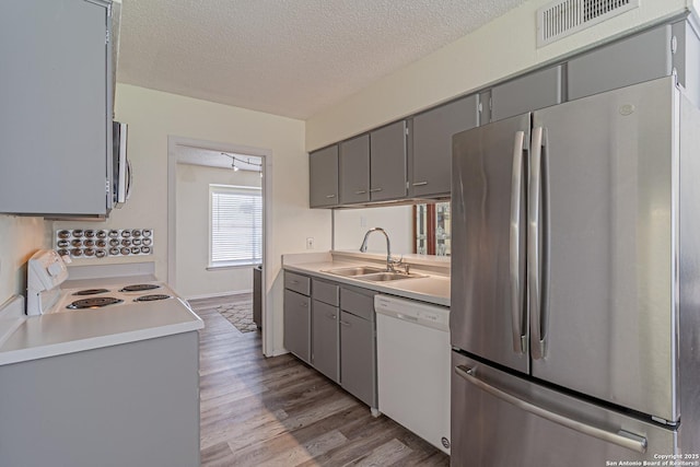 5718 Ponderosa Dr, San Antonio, TX 78240 - kitchen featuring stainless steel appliances, gray cabinetry, a sink, a textured ceiling, and wood finished floors