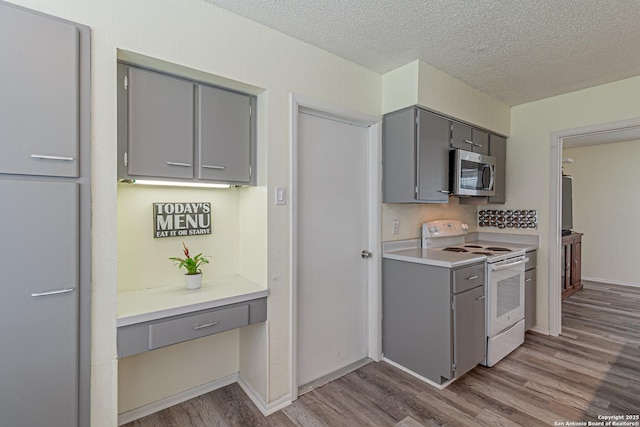 5718 Ponderosa Dr, San Antonio, TX 78240 - kitchen with gray cabinetry, electric stove, stainless steel microwave, wood finished floors, and a textured ceiling
