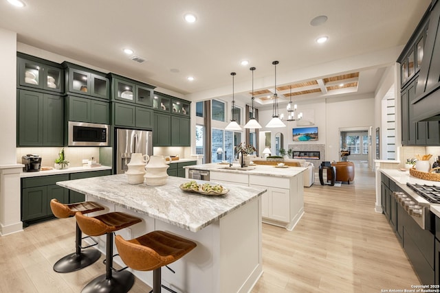 411 Poe Pkwy, Castroville, TX 78009 - kitchen with a kitchen island with sink, stainless steel appliances, green cabinetry, light wood-style flooring, and recessed lighting