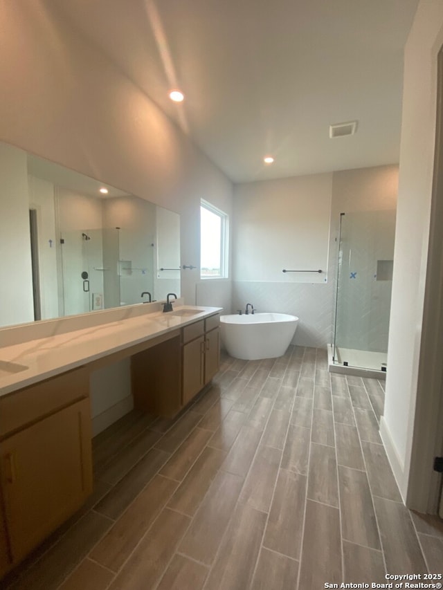 1641 Saddleback Run, New Braunfels, TX 78130 - bathroom with a stall shower, wood finished floors, a freestanding bath, double vanity, and recessed lighting