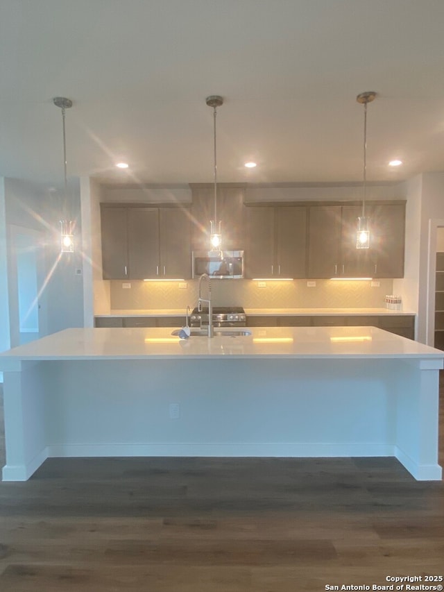 2046 Newforest Peak, New Braunfels, TX 78130 - kitchen featuring light countertops, stainless steel microwave, a large island with sink, dark wood-style floors, and recessed lighting