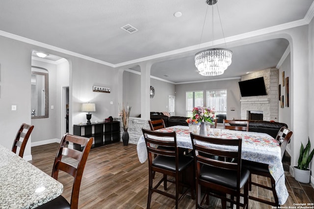 23534 Enchanted Bnd, San Antonio, TX 78260 - dining space featuring dark wood-style floors, ornamental molding, a fireplace, baseboards, and a chandelier