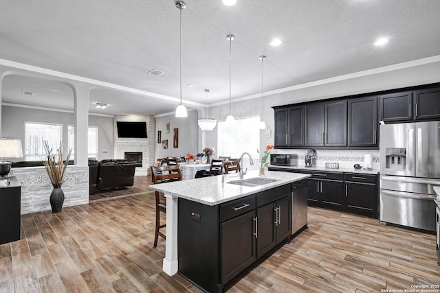 23534 Enchanted Bnd, San Antonio, TX 78260 - kitchen with appliances with stainless steel finishes, a sink, open floor plan, a breakfast bar area, and a large fireplace