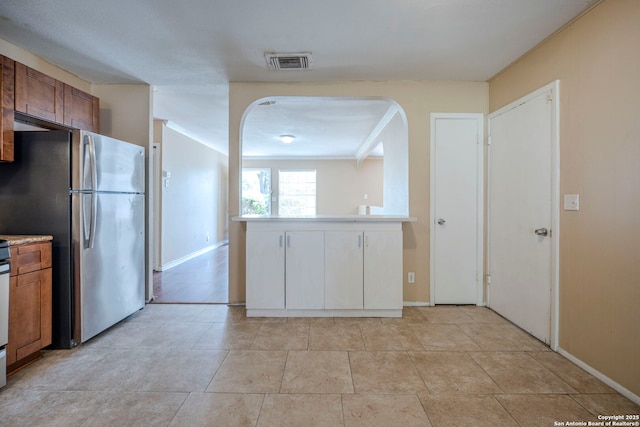 12231 El Santo Way, San Antonio, TX 78233 - kitchen featuring freestanding refrigerator, arched walkways, brown cabinets, and baseboards