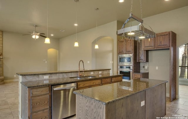 121 E Ashton, Floresville, TX 78114 - kitchen featuring arched walkways, appliances with stainless steel finishes, a sink, a center island with sink, and recessed lighting