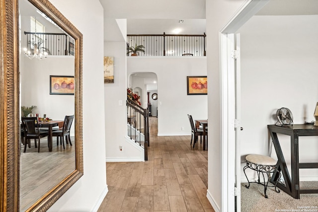 104 Mossy Bank, Cibolo, TX 78108 - hallway with arched walkways, light wood-style flooring, baseboards, stairs, and a chandelier