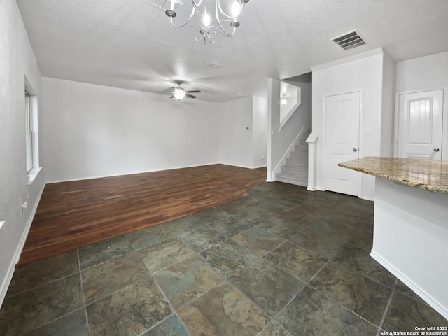 204 Bridle, Cibolo, TX 78108 - unfurnished living room with stone tile floors, stairway, baseboards, a chandelier, and a textured ceiling