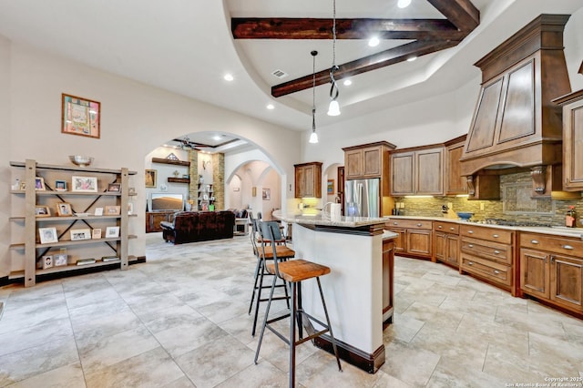 kitchen with appliances with stainless steel finishes, arched walkways, tasteful backsplash, a kitchen breakfast bar, and beamed ceiling