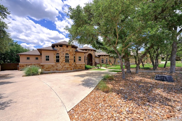 mediterranean / spanish-style house with stone siding and driveway