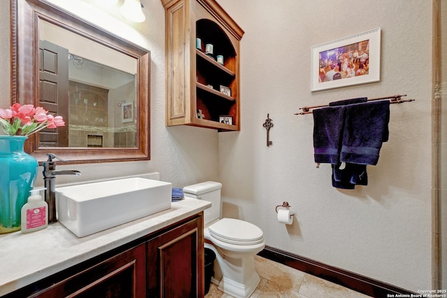 bathroom with baseboards, toilet, and vanity