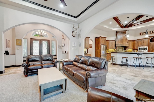 living area with arched walkways, beam ceiling, a high ceiling, recessed lighting, and a chandelier