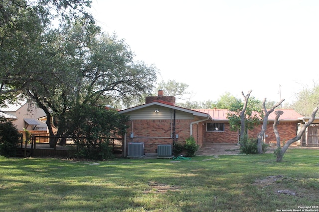 355 Donella, Hollywood Park, TX 78232 - rear view of house with central AC unit, a yard, brick siding, and a chimney