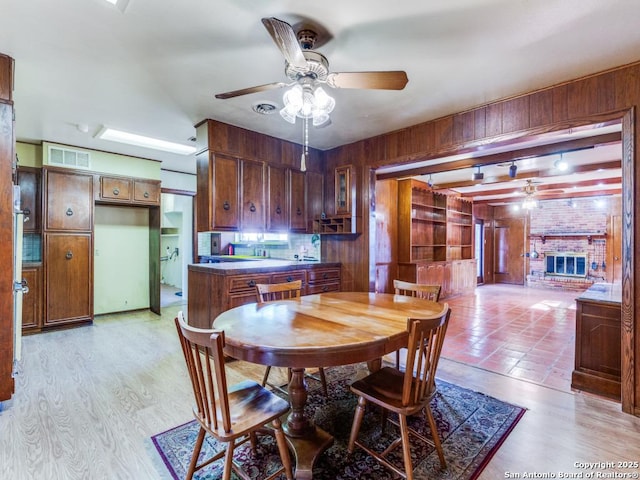 355 Donella, Hollywood Park, TX 78232 - dining space featuring a ceiling fan, wooden walls, a fireplace, and light wood-style flooring