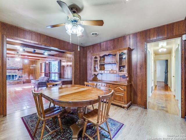 355 Donella, Hollywood Park, TX 78232 - dining space featuring wood walls, a ceiling fan, light wood-type flooring, and a brick fireplace